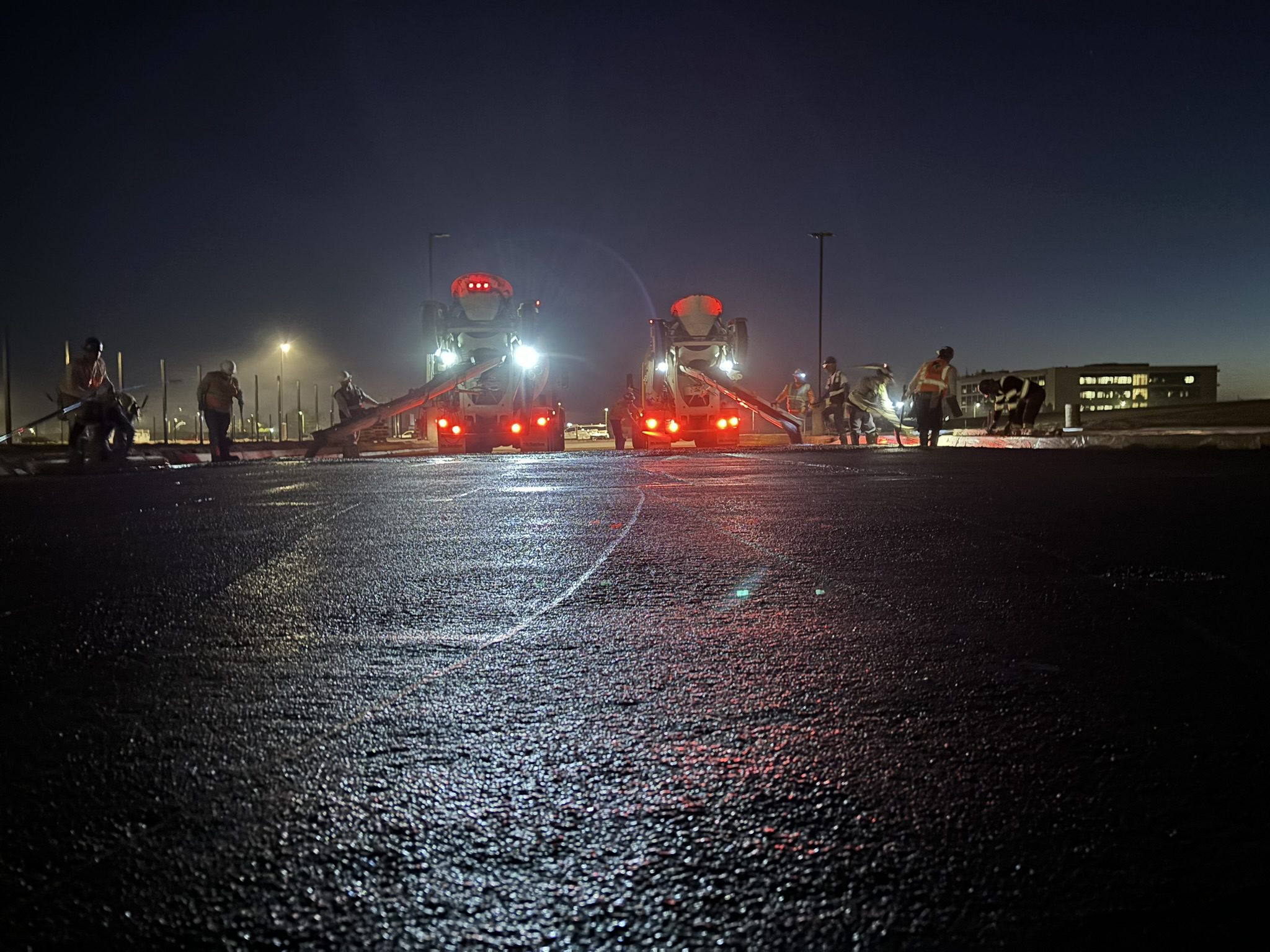 A couple of trains are on the tracks at night.