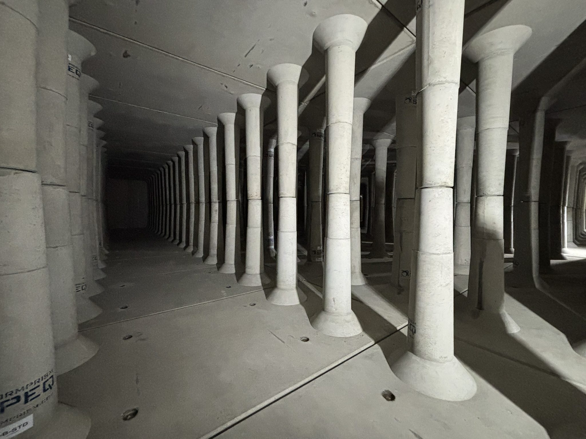 A long hallway with many pillars and concrete floors.