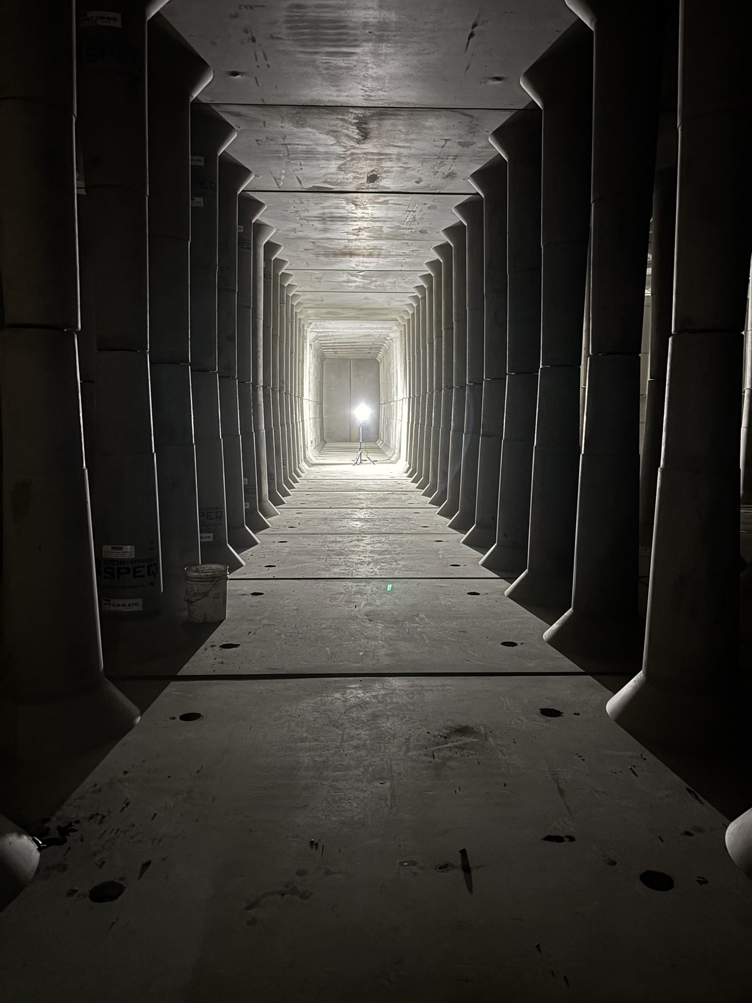 A long hallway with pillars and lights in the center.